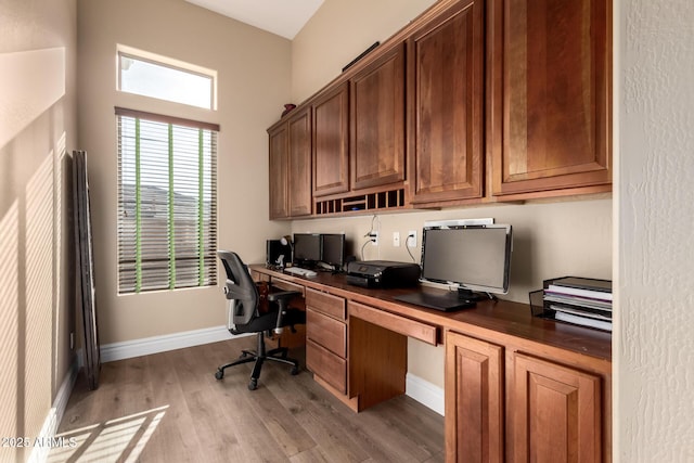 home office with built in desk and light hardwood / wood-style floors