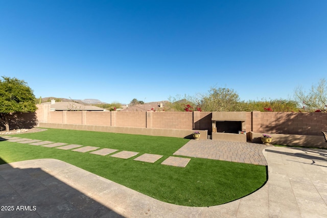 view of yard featuring an outdoor fireplace and a patio area