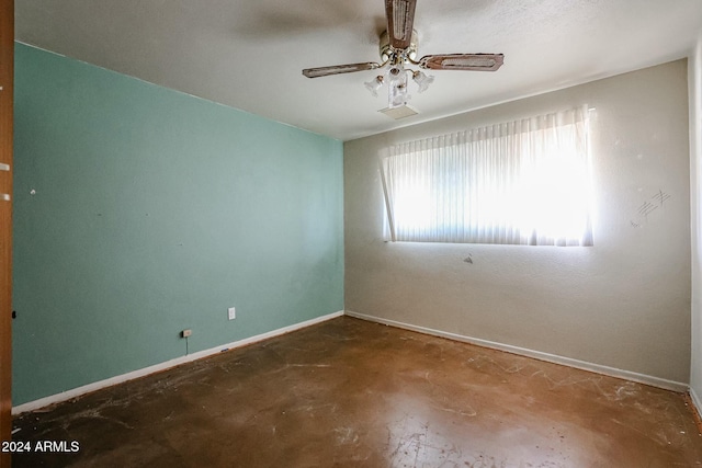 empty room with ceiling fan and concrete flooring