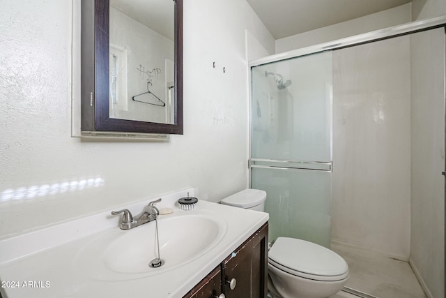 bathroom featuring vanity, toilet, and a shower with shower door