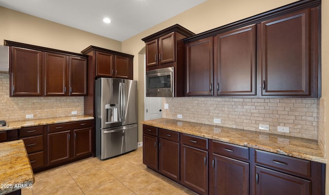 kitchen with light tile patterned floors, backsplash, appliances with stainless steel finishes, and light stone counters