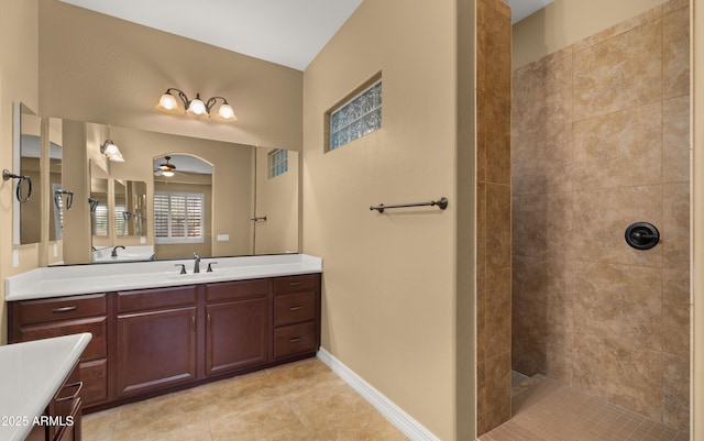 bathroom featuring tile patterned flooring, baseboards, walk in shower, vanity, and a ceiling fan