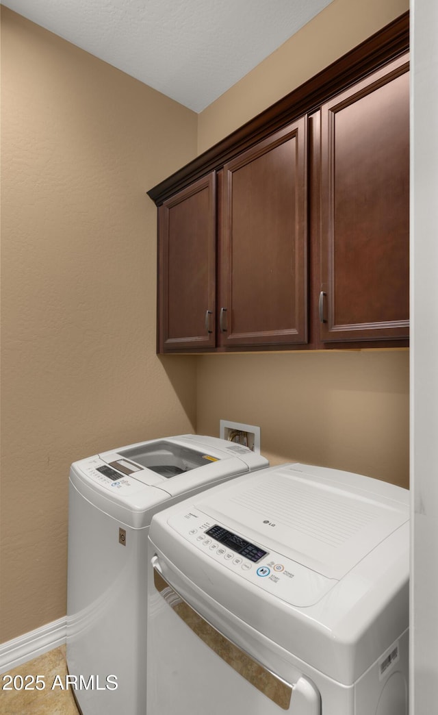 laundry area featuring baseboards, cabinet space, washing machine and dryer, and light tile patterned flooring