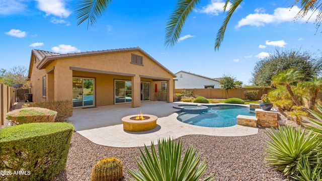 view of pool featuring a patio area, a pool with connected hot tub, an outdoor fire pit, and a fenced backyard