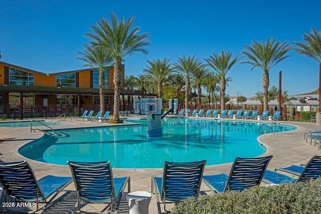 community pool with a patio and fence