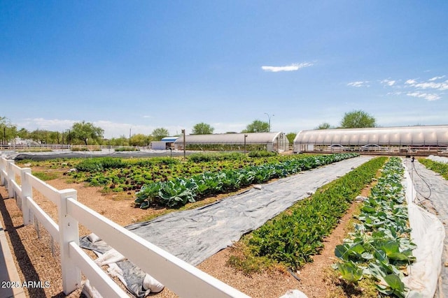 view of community with a rural view, fence, an outdoor structure, and a garden