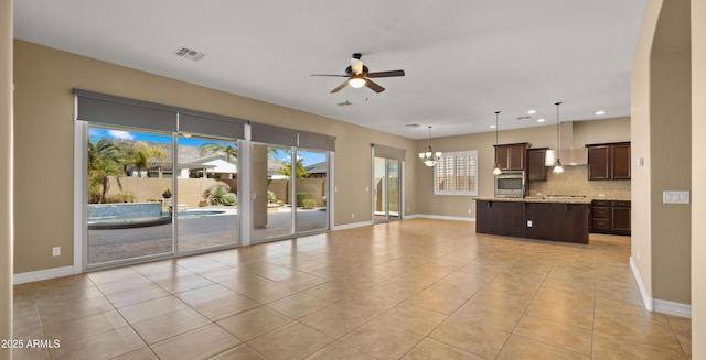 unfurnished living room with visible vents, ceiling fan with notable chandelier, recessed lighting, light tile patterned flooring, and baseboards