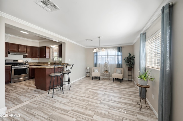 405 W Monte Way, Phoenix, AZ 85041 - kitchen with stainless steel range with gas cooktop, under cabinet range hood, healthy amount of natural light, a breakfast bar, and crown molding