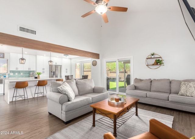 living room featuring hardwood / wood-style floors, ceiling fan, and a high ceiling