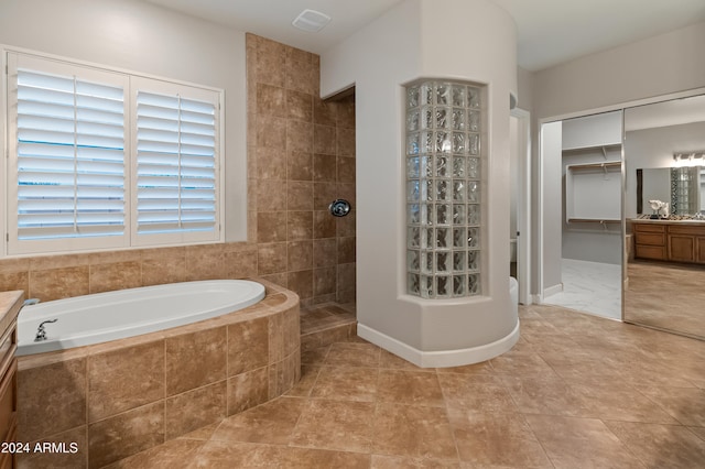 bathroom featuring tile patterned flooring, shower with separate bathtub, and vanity