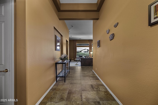 hall featuring baseboards and stone finish flooring
