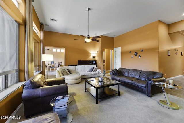 carpeted living area with visible vents, baseboards, a ceiling fan, and a healthy amount of sunlight