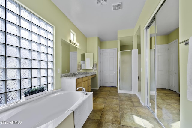 full bath with a stall shower, a garden tub, vanity, and visible vents