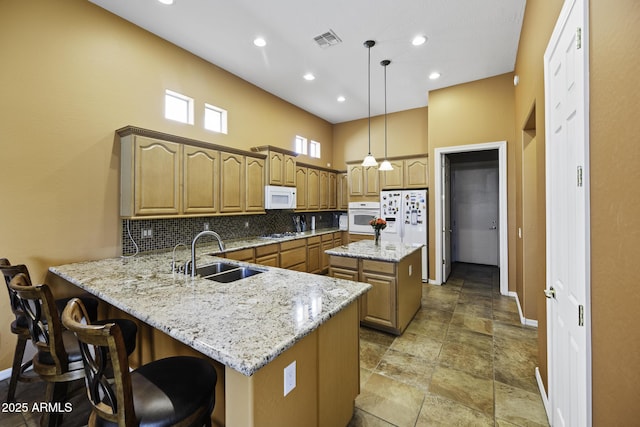 kitchen featuring baseboards, white appliances, a peninsula, visible vents, and a sink