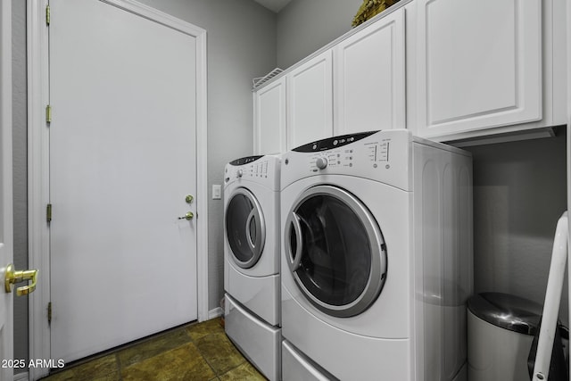 washroom with washer and dryer, stone finish flooring, and cabinet space