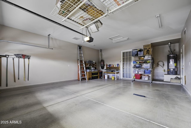 garage with a garage door opener, baseboards, gas water heater, and visible vents