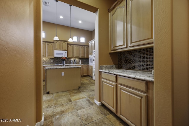 kitchen with white appliances, stone finish floor, visible vents, a center island, and backsplash