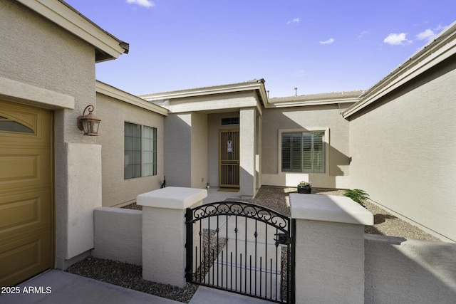 doorway to property featuring fence, a gate, a garage, and stucco siding