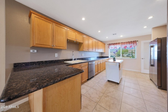 kitchen with appliances with stainless steel finishes, recessed lighting, a sink, and dark stone countertops