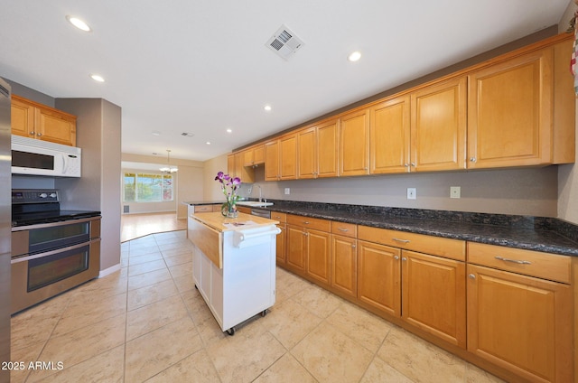 kitchen featuring visible vents, white microwave, double oven range, a sink, and recessed lighting