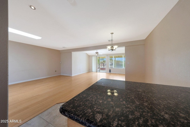 empty room featuring wood finished floors, baseboards, and an inviting chandelier