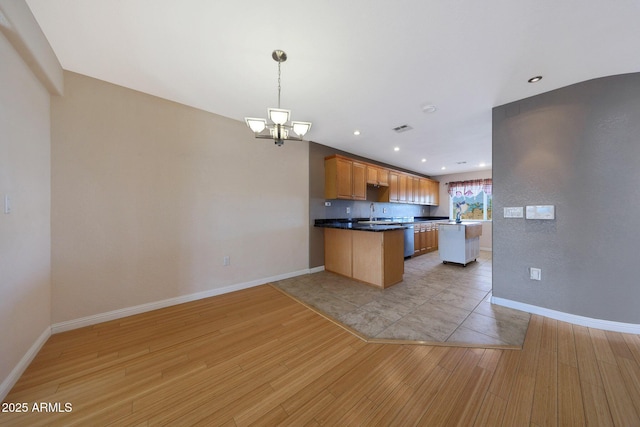 kitchen with light wood-type flooring, baseboards, a peninsula, and a chandelier