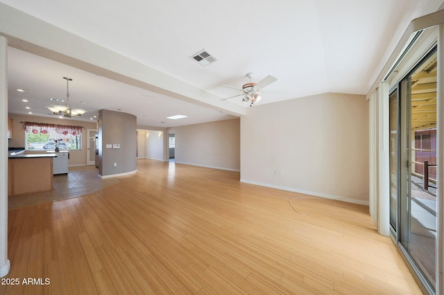 unfurnished living room with visible vents, light wood-style floors, vaulted ceiling, baseboards, and ceiling fan with notable chandelier