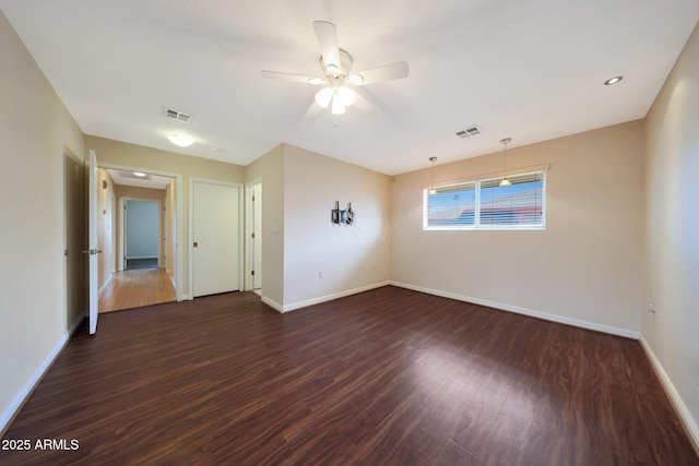 unfurnished room featuring baseboards, visible vents, and dark wood finished floors