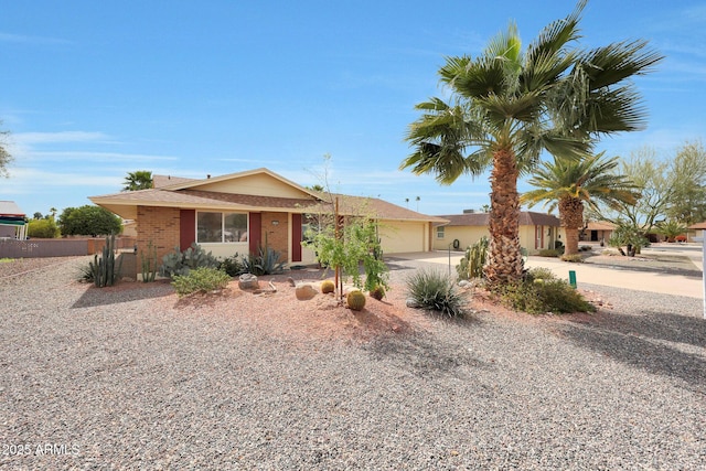 ranch-style house with an attached garage, fence, concrete driveway, and brick siding