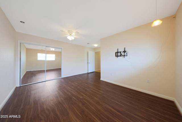 unfurnished bedroom featuring a closet, baseboards, and dark wood-style flooring