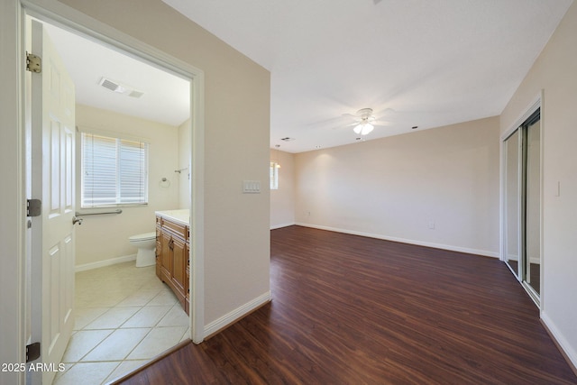 hallway with a healthy amount of sunlight, baseboards, visible vents, and light wood finished floors