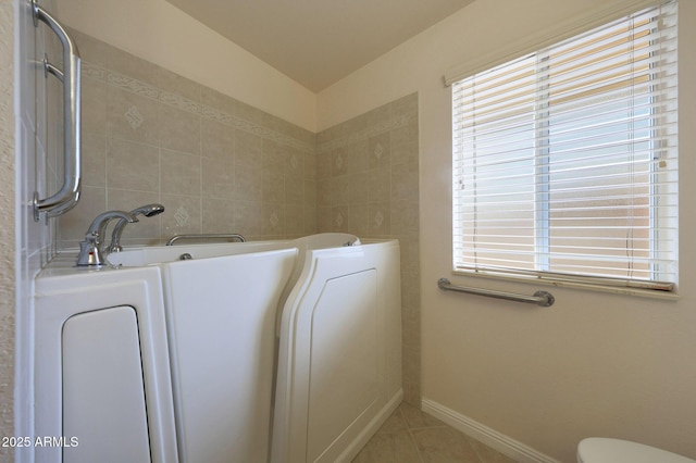 bathroom featuring a bathtub, tile walls, toilet, baseboards, and tile patterned floors