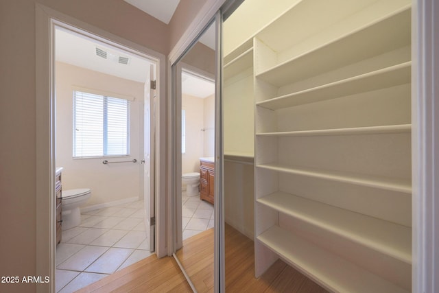 interior space featuring toilet, tile patterned flooring, visible vents, and baseboards