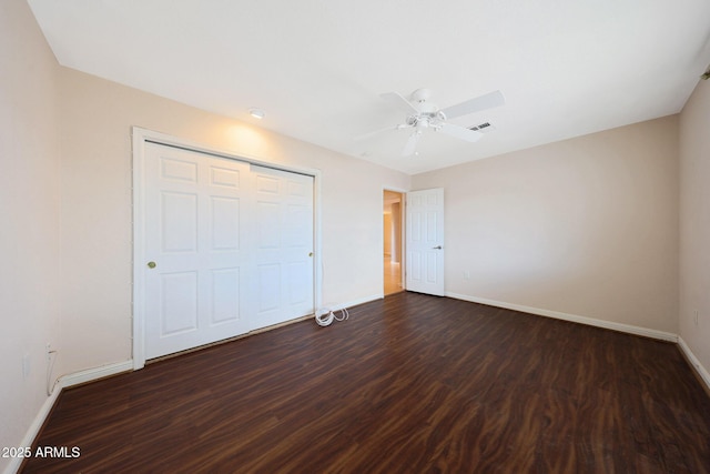 unfurnished bedroom with a ceiling fan, visible vents, baseboards, a closet, and dark wood-style floors