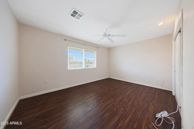 unfurnished room featuring a ceiling fan, visible vents, dark wood finished floors, and baseboards