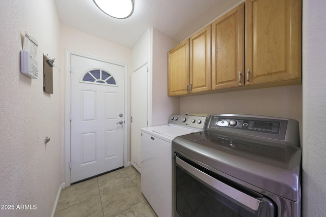 washroom featuring cabinet space, light tile patterned flooring, and washing machine and clothes dryer