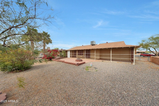 rear view of property featuring an outdoor fire pit, a sunroom, a patio area, fence, and central AC