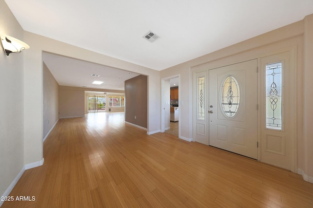 entrance foyer with light wood finished floors, baseboards, visible vents, and washer / clothes dryer