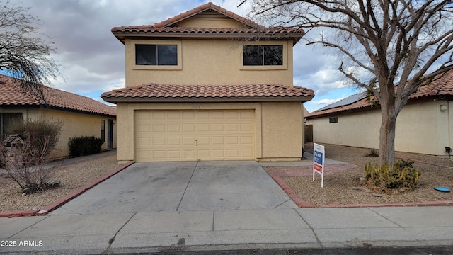 mediterranean / spanish home with an attached garage, a tile roof, concrete driveway, and stucco siding