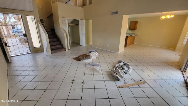 foyer entrance with stairs, light tile patterned flooring, a towering ceiling, and visible vents