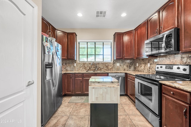 kitchen with light tile flooring, a center island, tasteful backsplash, and stainless steel appliances