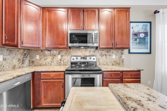 kitchen with light stone counters, backsplash, and stainless steel appliances