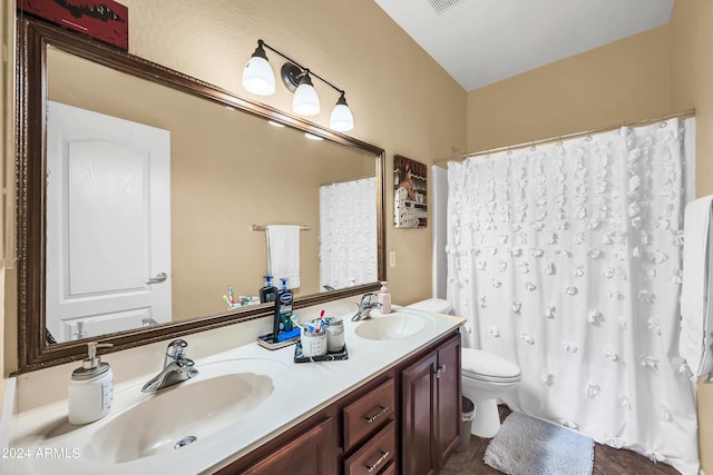 bathroom featuring vanity with extensive cabinet space, toilet, and double sink