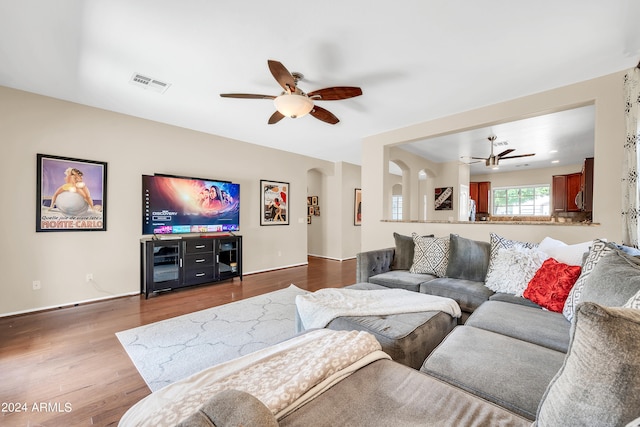 living room featuring ceiling fan and dark hardwood / wood-style flooring