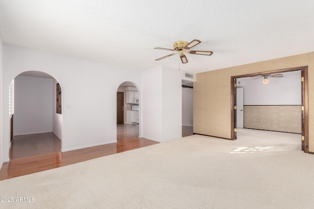 carpeted spare room featuring a textured ceiling and ceiling fan