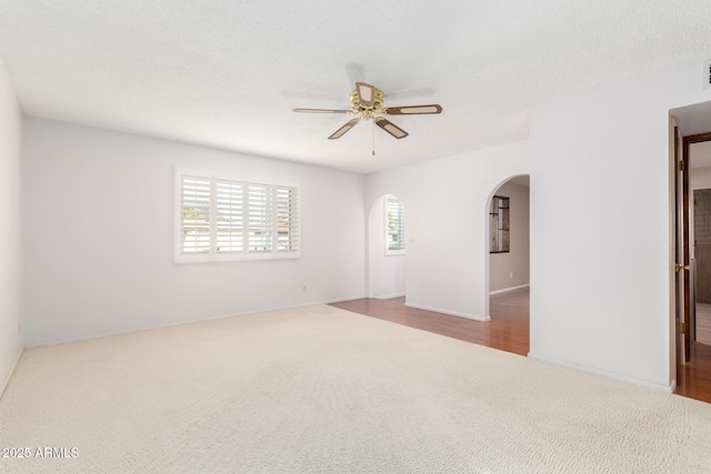 spare room with ceiling fan, light carpet, and a textured ceiling