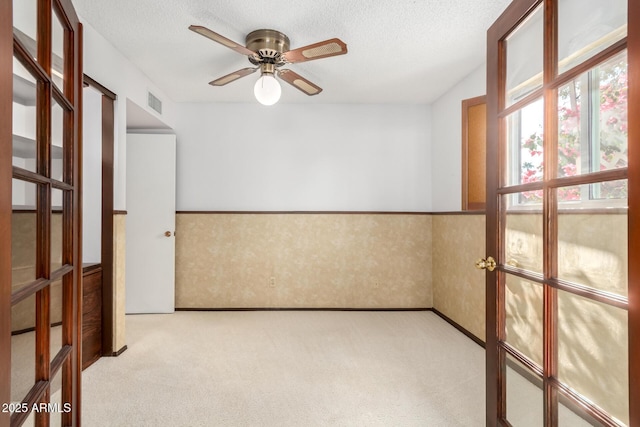 unfurnished room featuring ceiling fan, light carpet, and a textured ceiling