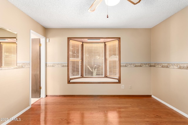 empty room featuring ceiling fan, light hardwood / wood-style floors, and a textured ceiling