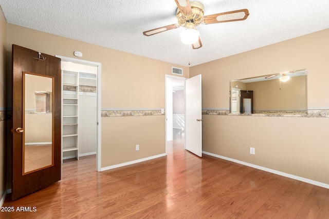 unfurnished room with ceiling fan, wood-type flooring, and a textured ceiling