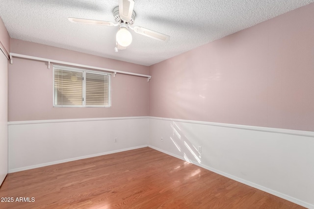 unfurnished room featuring ceiling fan, wood-type flooring, and a textured ceiling